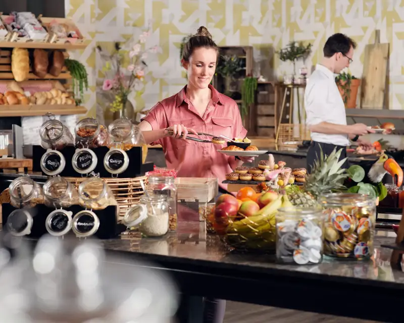 Dame steht am Frühstücksbuffet