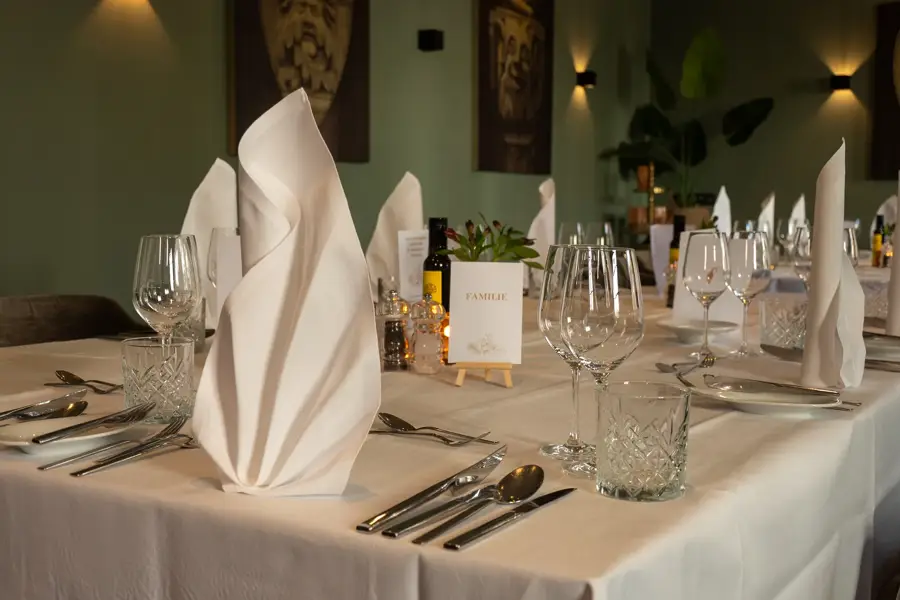 Close-up of a festively set table with white cloth napkins, glasses and cutlery at the Van der Valk Hotel Hildesheim.