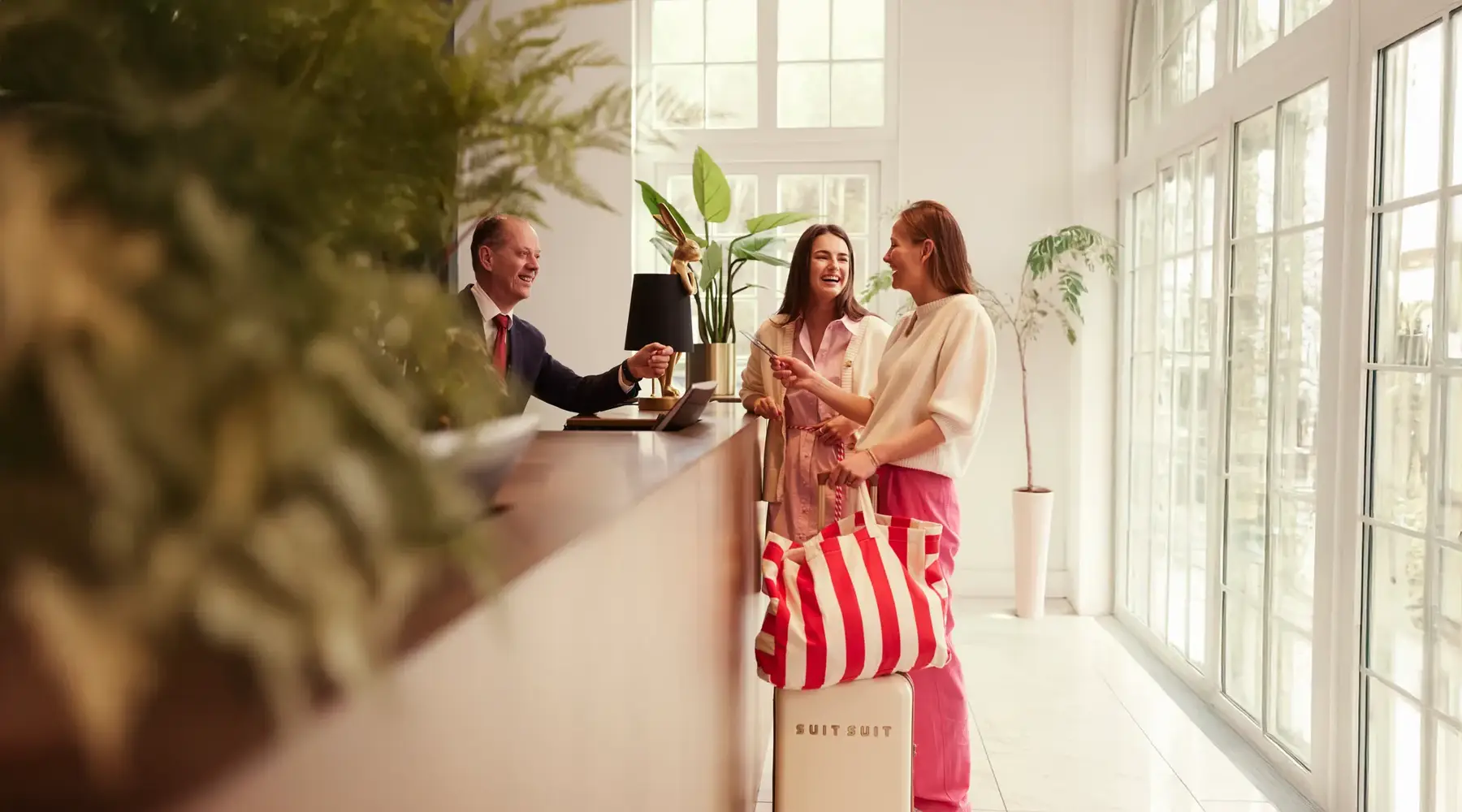 Female friends check in at the reception of a hotel.