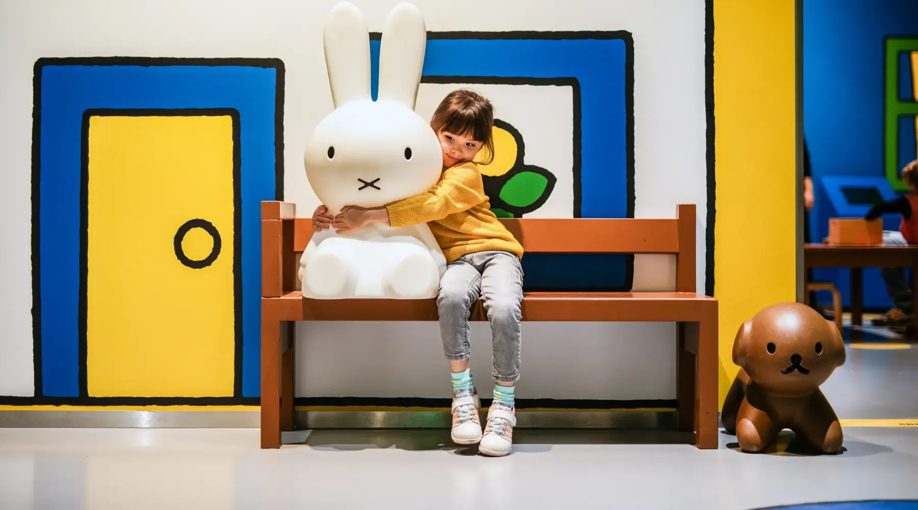 A child is hugging Nijntje at the Nijntje museum.