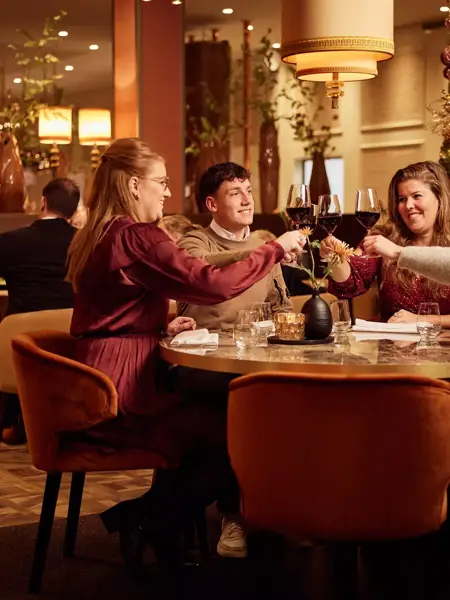 Friends toasting with glasses in a Christmas setting.