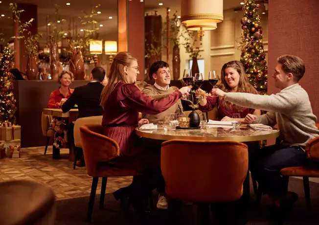 Vrienden aan tafel proosten in kerst setting