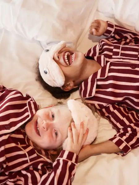 Kinder mit Schlafmaske in einem Hotelbett