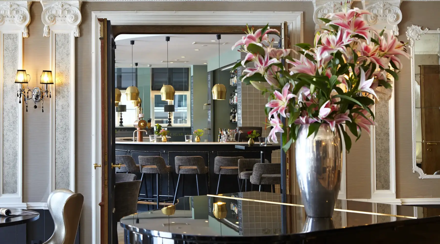 Eleganter Eingang zur Stadtschenke mit großer Blumenvase und Blick auf den Barbereich im Van der Valk Hotel Hildesheim.