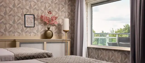 Comfortabele fauteuils bij het raam creëren een rustige zithoek in de hotelkamer