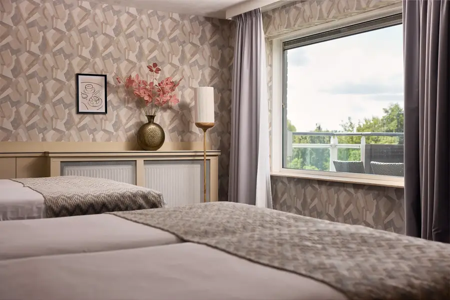 Comfortabele fauteuils bij het raam creëren een rustige zithoek in de hotelkamer