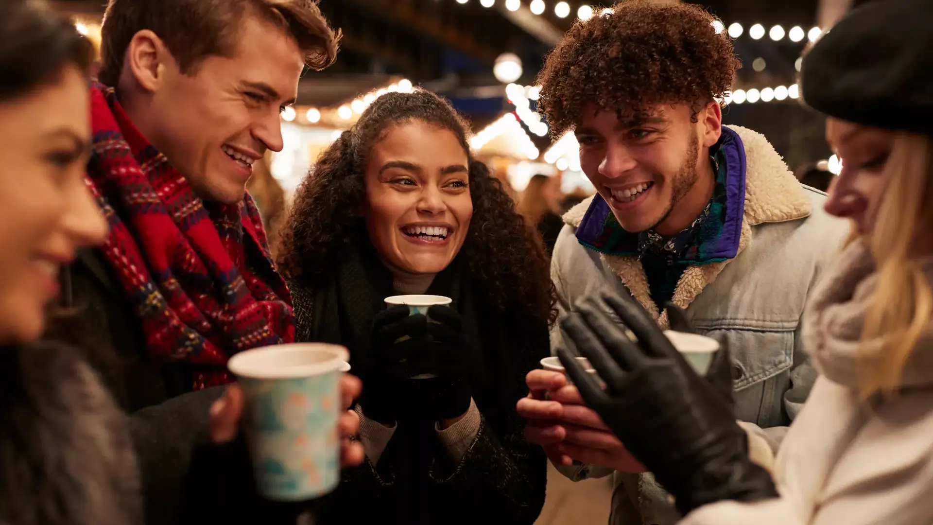 Vrienden die gezellig wat drinken tijdens een kerstmarkt