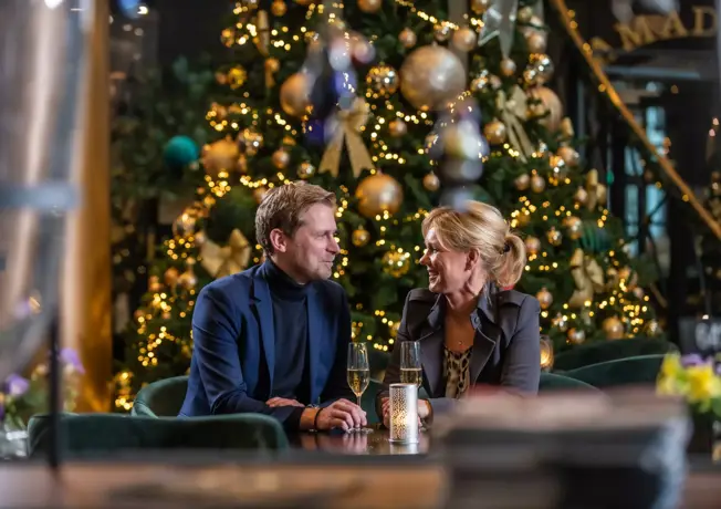 Paar am Tisch beim Weihnachtsbaum