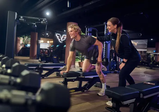 Lid met trainer in de fitness