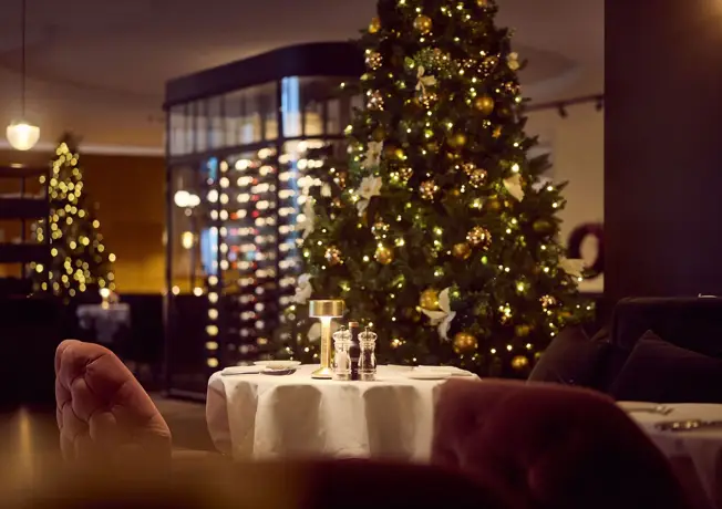 Stimmungsvoll gedeckter Tisch für das Weihnachtsdinner mit Kerzenlicht und festlichen Dekorationen.