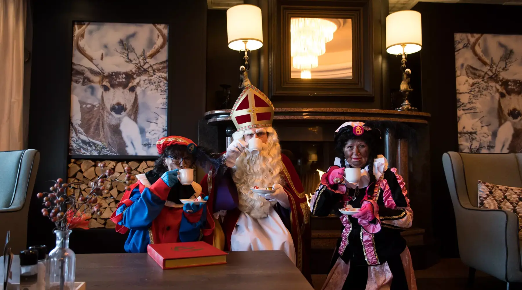 Sinterklaas drinkt koffie met zijn pieten