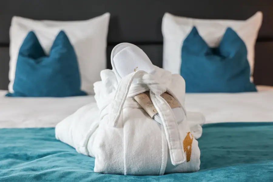 Bademäntel und Hausschuhe auf dem Bett in einem Executive-Zimmer im Van der Valk Hotel Hoorn.