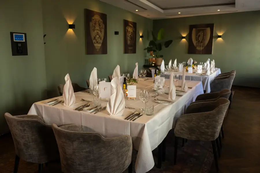 Festively decorated event room with a long table, white napkins and dark chairs in the Van der Valk Hotel Hildesheim.