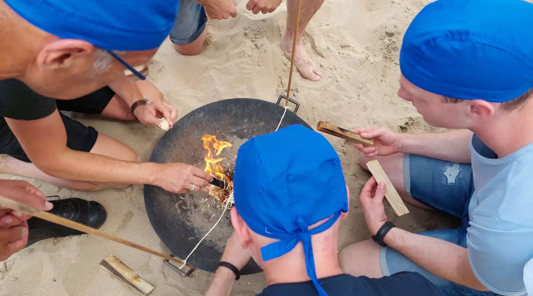 Groep maakt vuur op strand tijdens Expeditie Robinson proef.