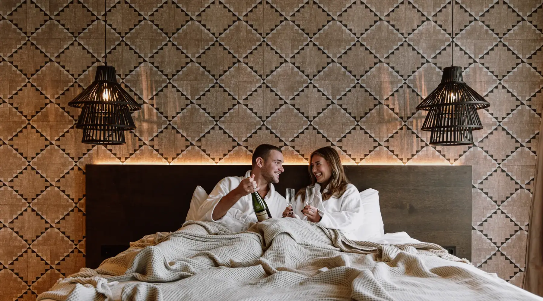 Un couple au lit avec du champagne.