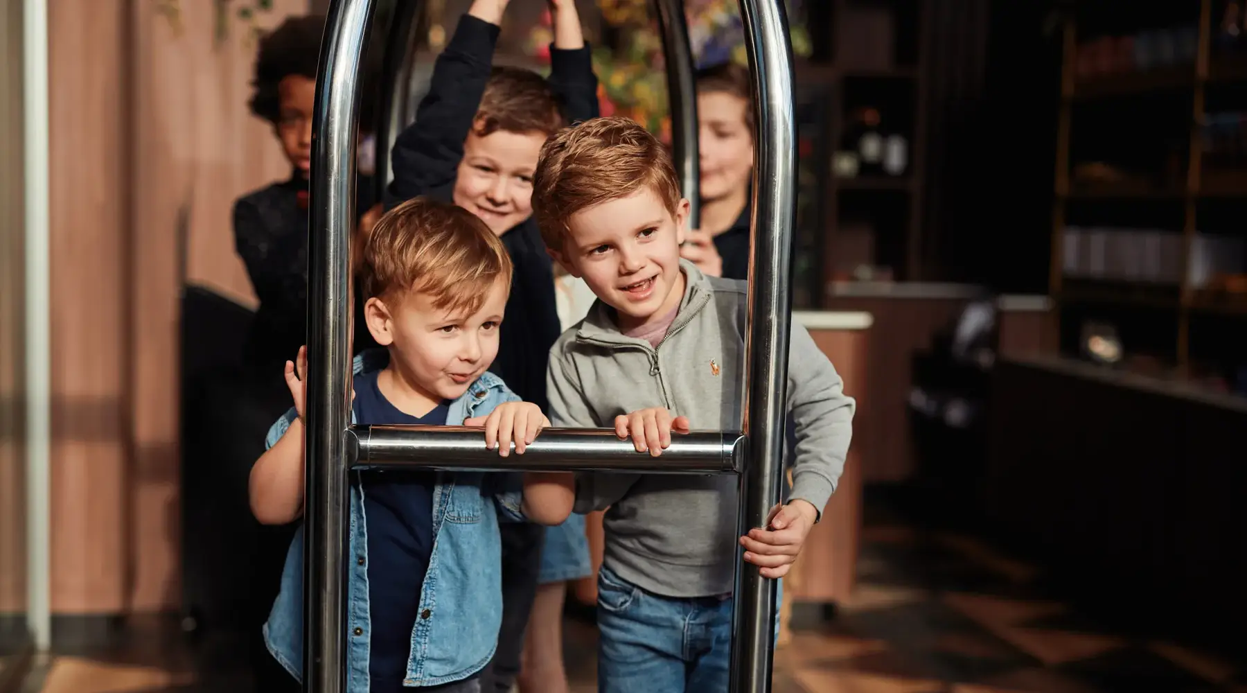 Children are playing on a luggage cart.
