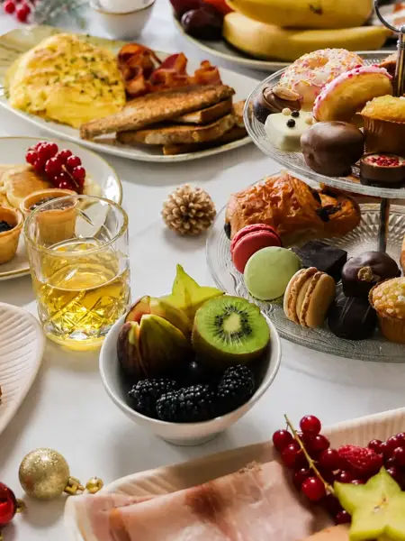 Brunch de Noël étendu avec divers plats salés et sucrés, fruits frais et décoration de Noël festive.