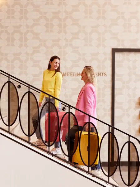 2 Frauen in bunter Kleidung steigen eine Treppe in einem Van der Valk Hotel hinauf
