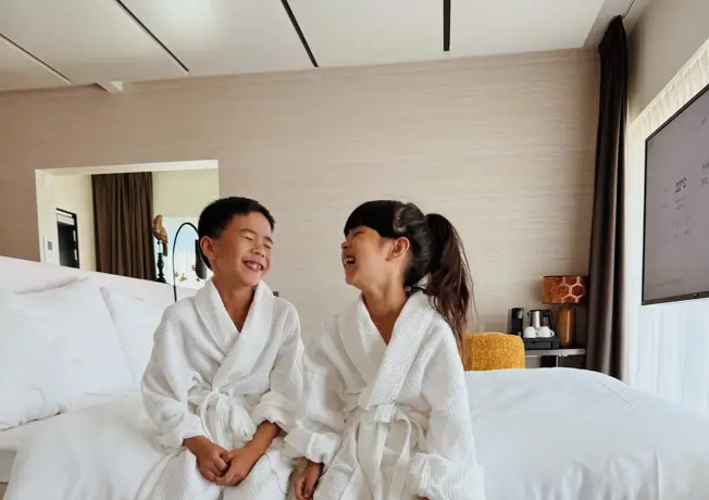 les enfants sont assis au bord du lit king-size dans la suite familiale