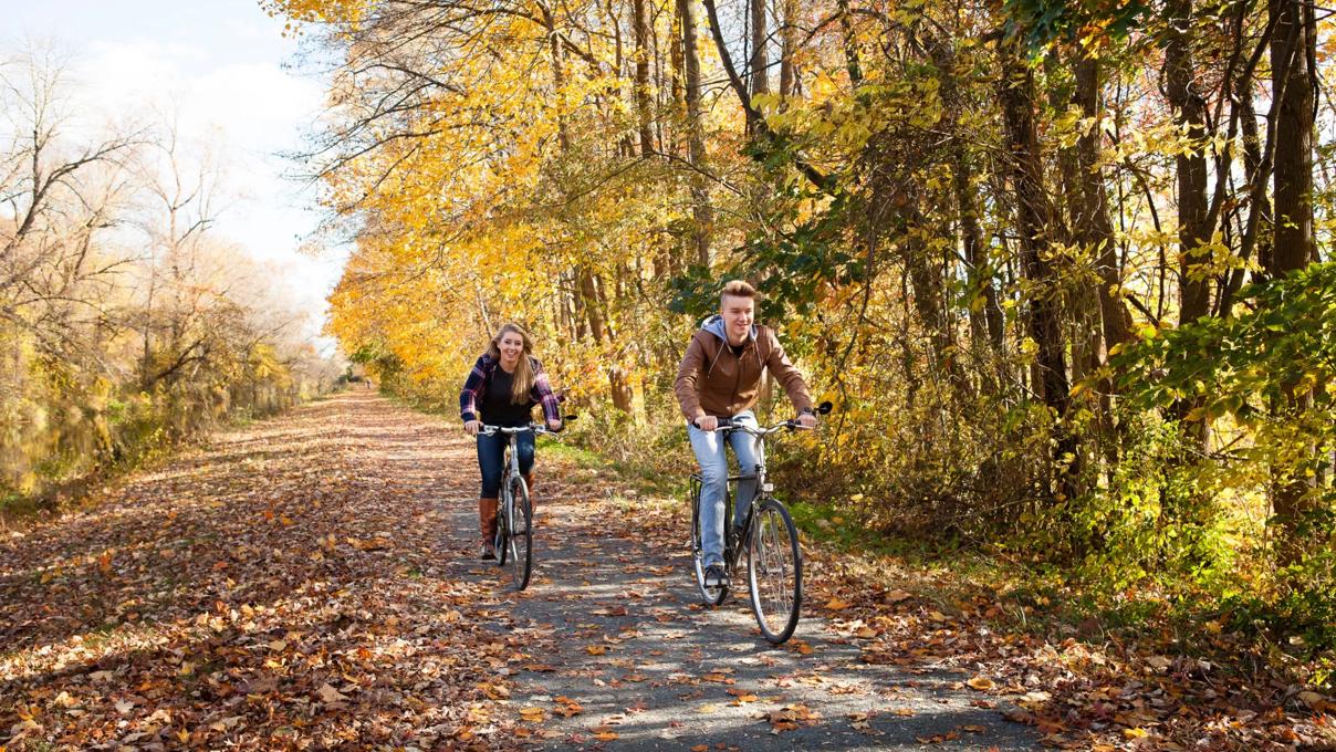 Broer en zus samen op de fiets in het bos tijdens de herfst