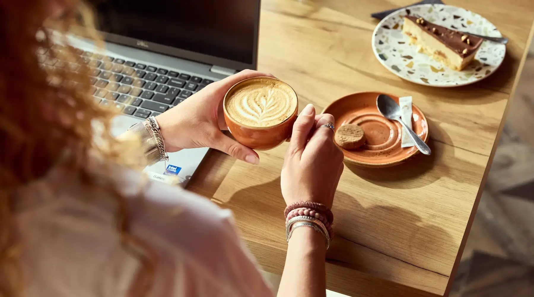 Vrouw achter laptop met koffie en taart 