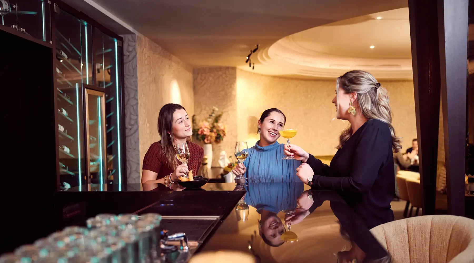 Drie dames die een drankje drinken aan de bar