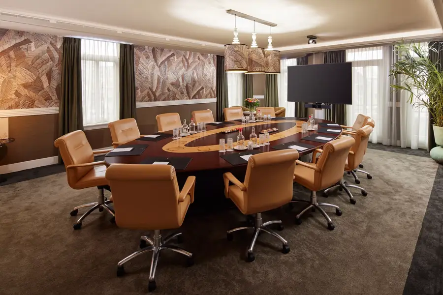 Overzichtsfoto van Dahlia Boardroom met ovale tafel, oranje draaistoelen, daglicht en scherm
