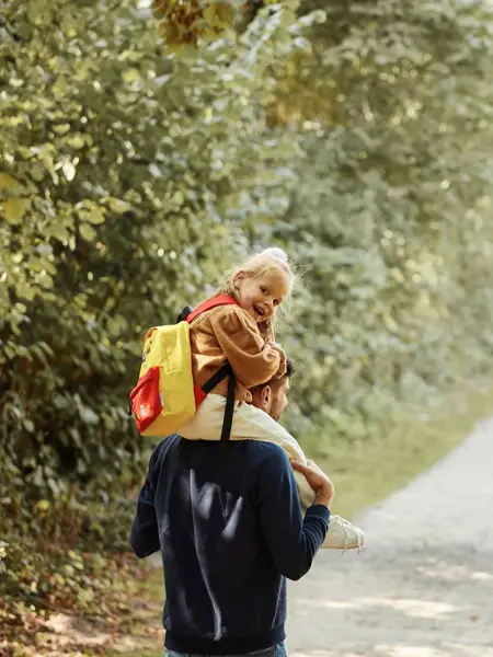 Vater mit Tochter auf den Schultern im Wald
