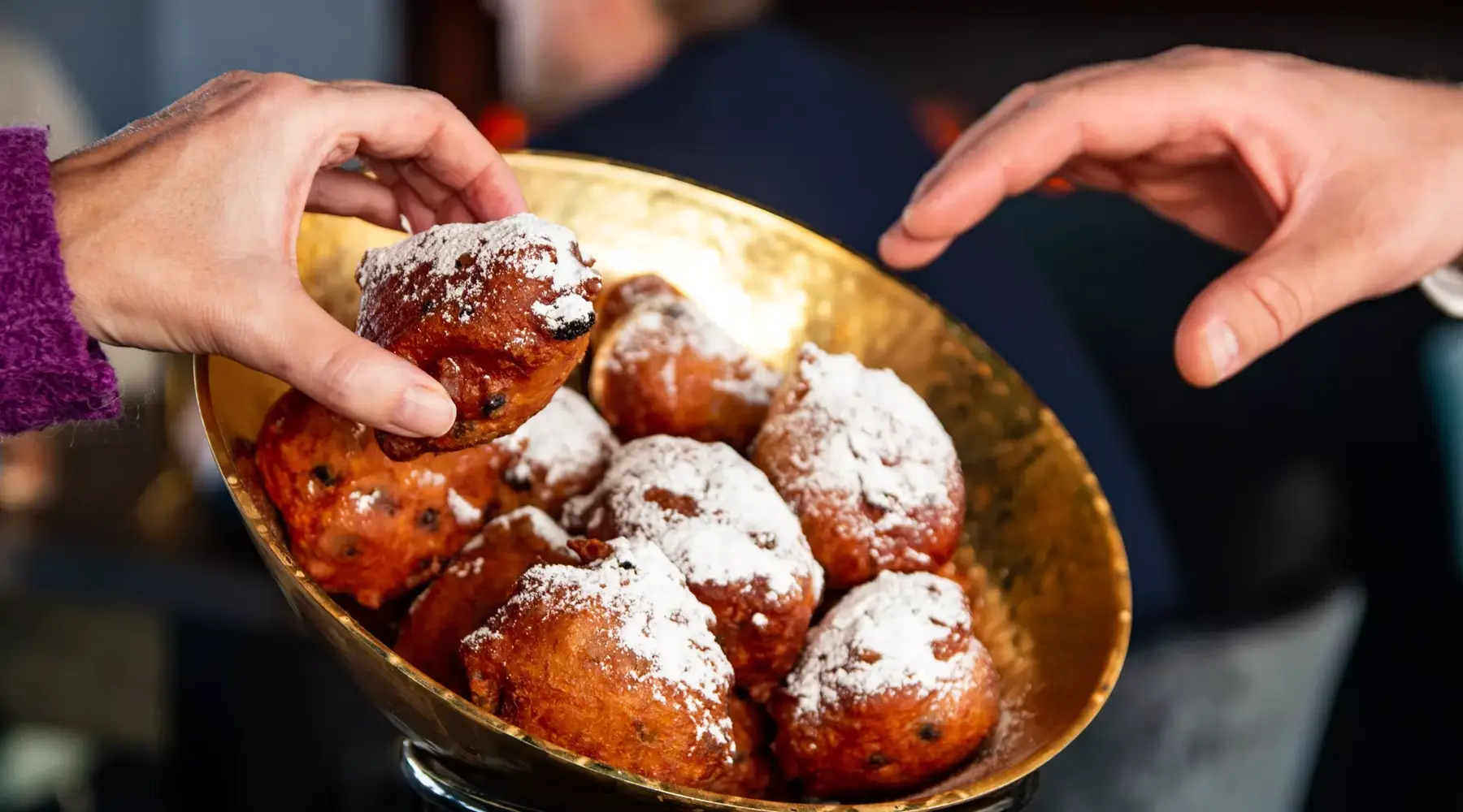 Mensen pakken oliebollen uit een schaal.