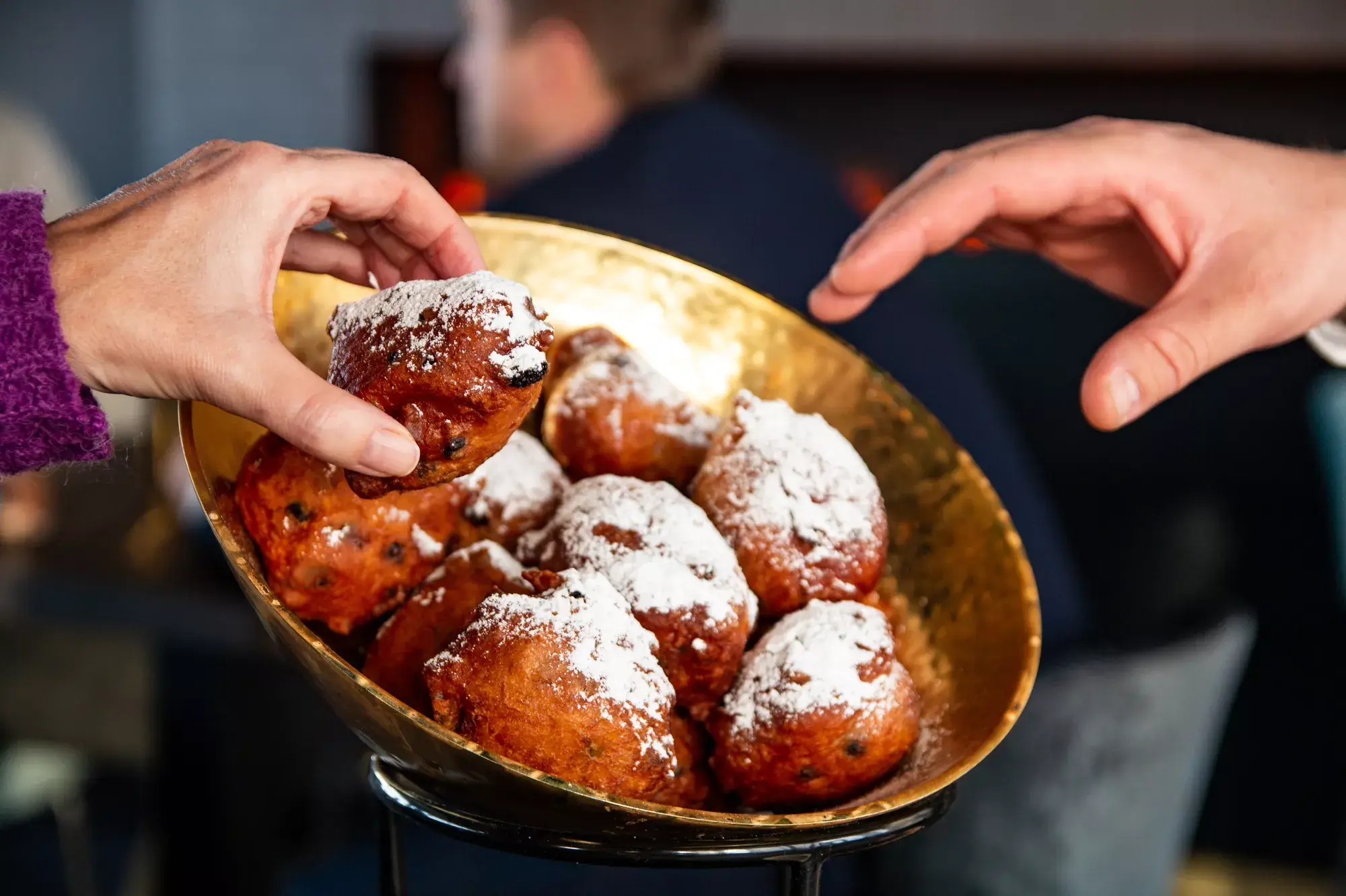 Die Leute nehmen Oliebollen aus einer Schüssel.