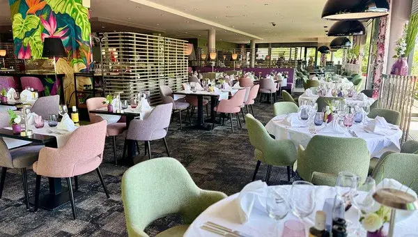 Pastellfarbene Stühle und gedeckte Tische im Restaurant des Hotels Charleroi Airport