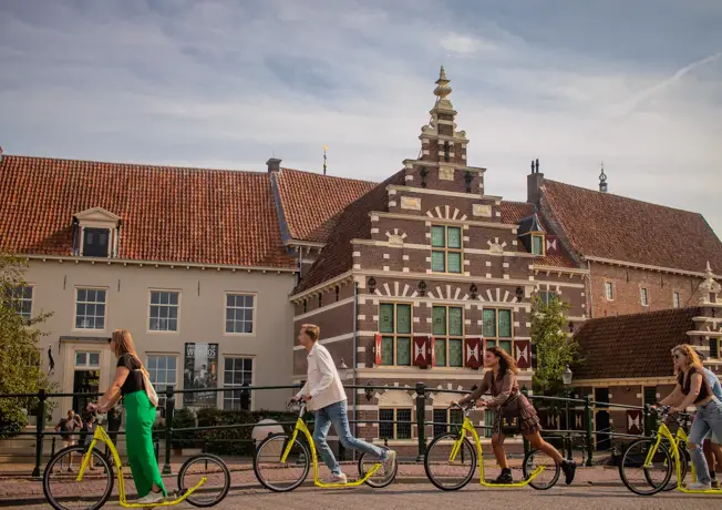 een huis in de stad en wat mensen op een fiets
