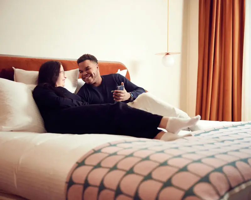 Een stel ligt op het hotelbed