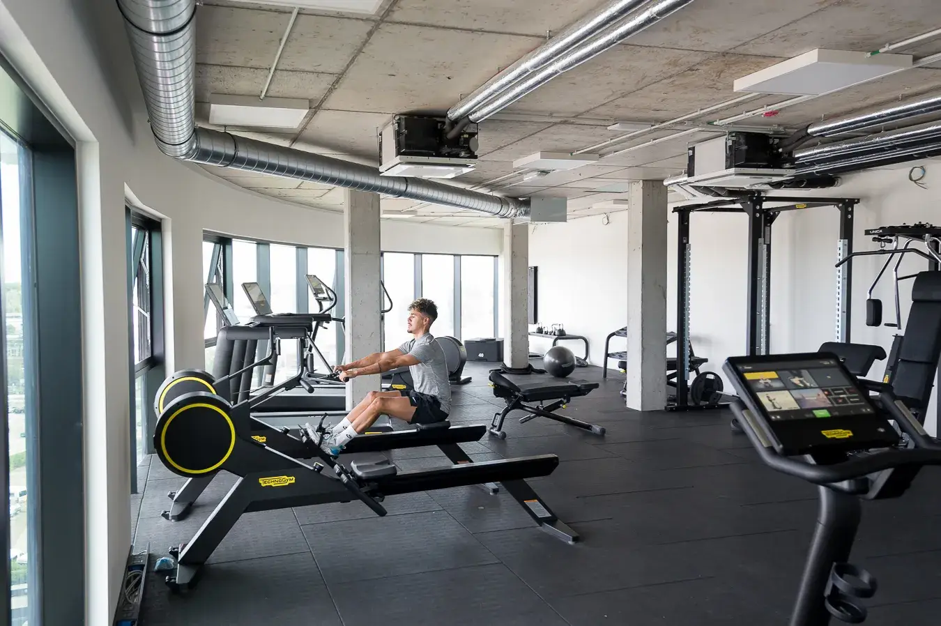 Young man sitting on the rowing machine in the gym of Hotel Gent