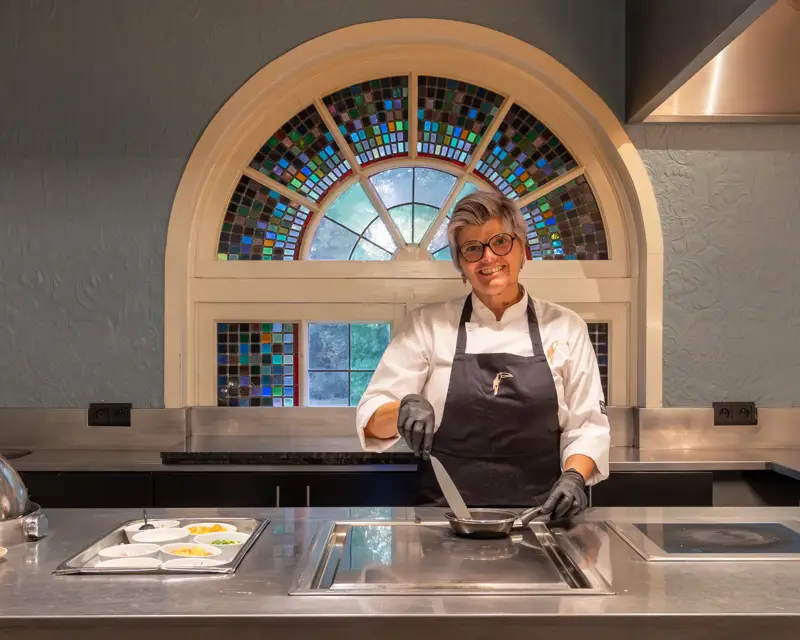 Une femme est en train de cuire des œufs au stand de cuisine en direct.