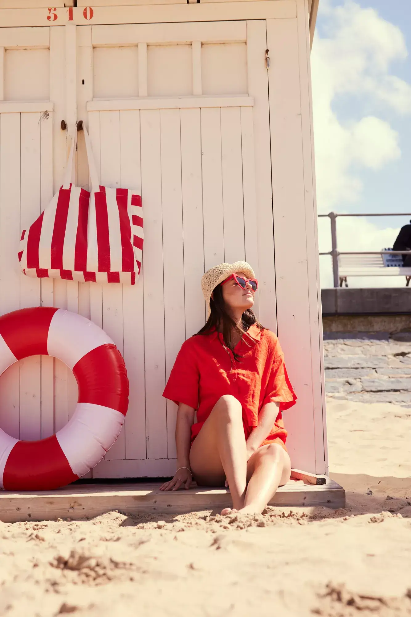 Une fille profite du soleil contre une cabine de plage 