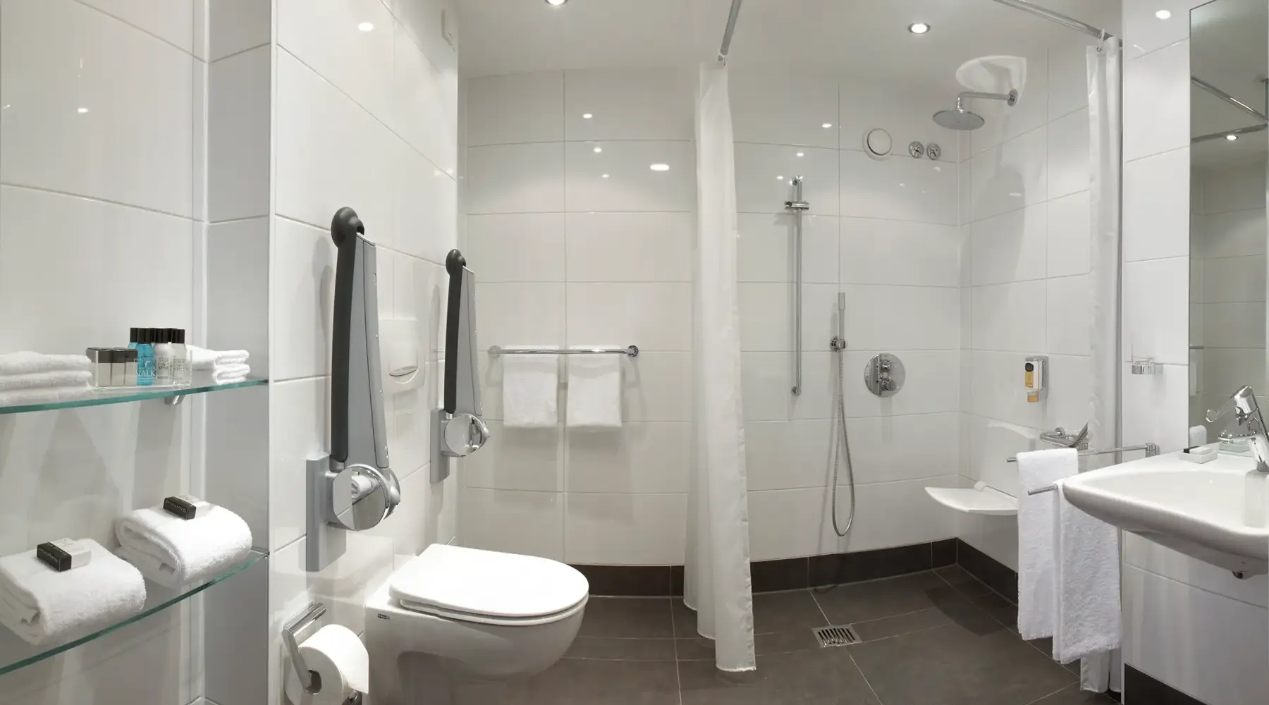 Wheelchair-accessible bathroom with level-access shower, shower seat, grab rails and accessible washbasin