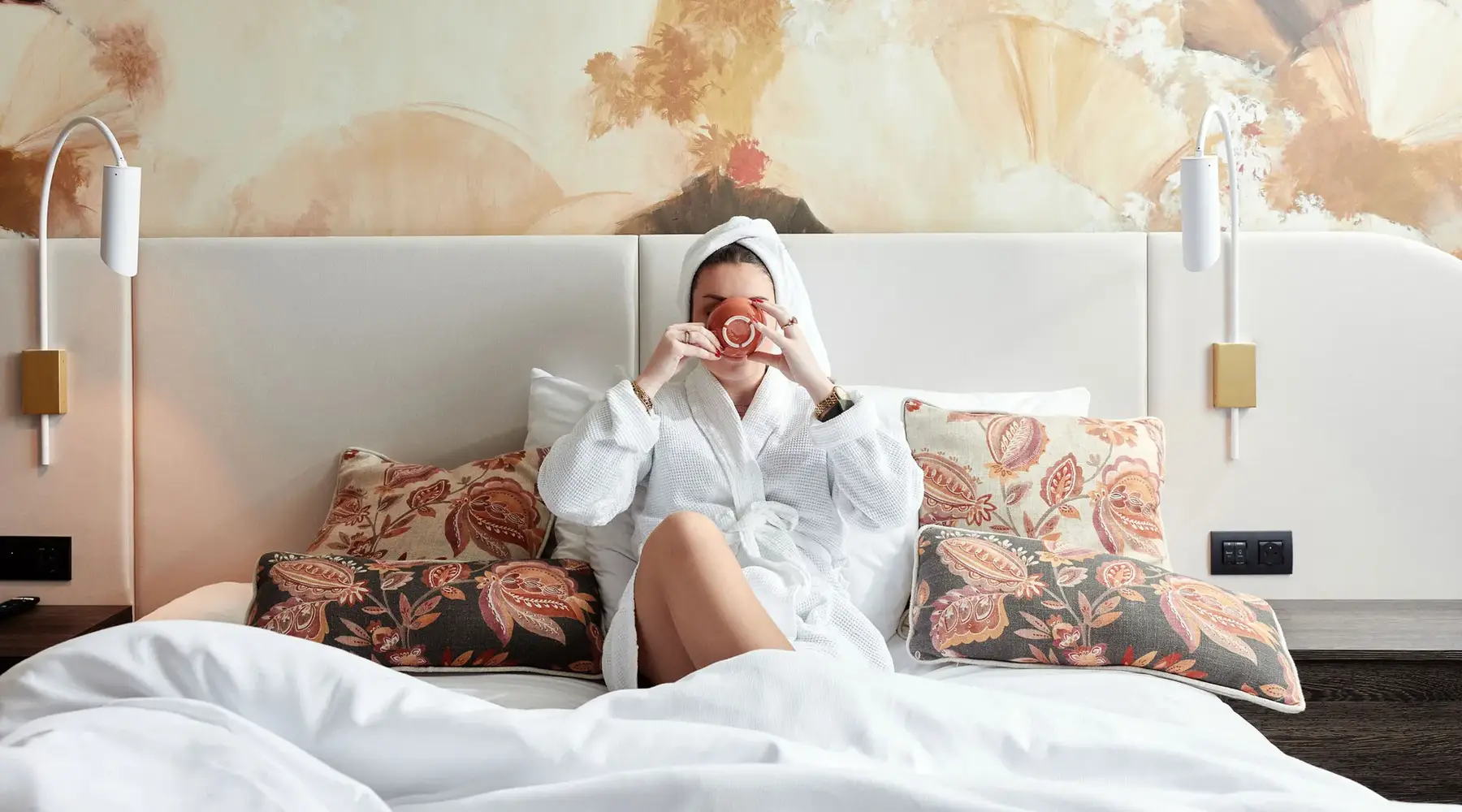 Vrouw in een hotelbed met een kop koffie