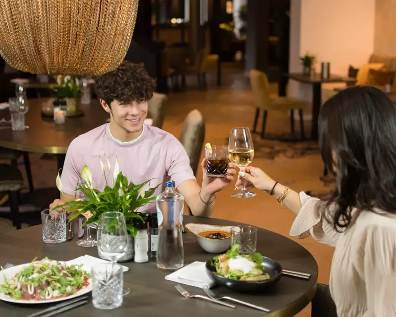 A girl and a boy with a drink in hand.