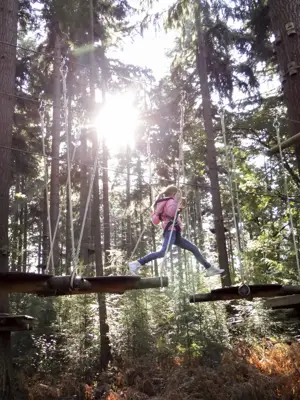 Girl with a pink jacket doing a high ropes course.