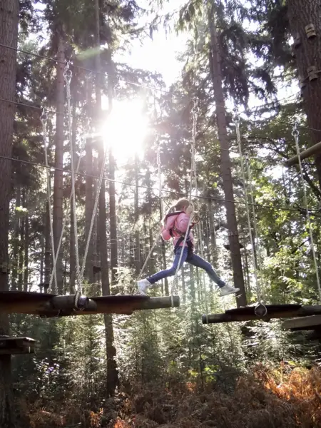 Meisje met roze jas die een hoogteparcours aflegd