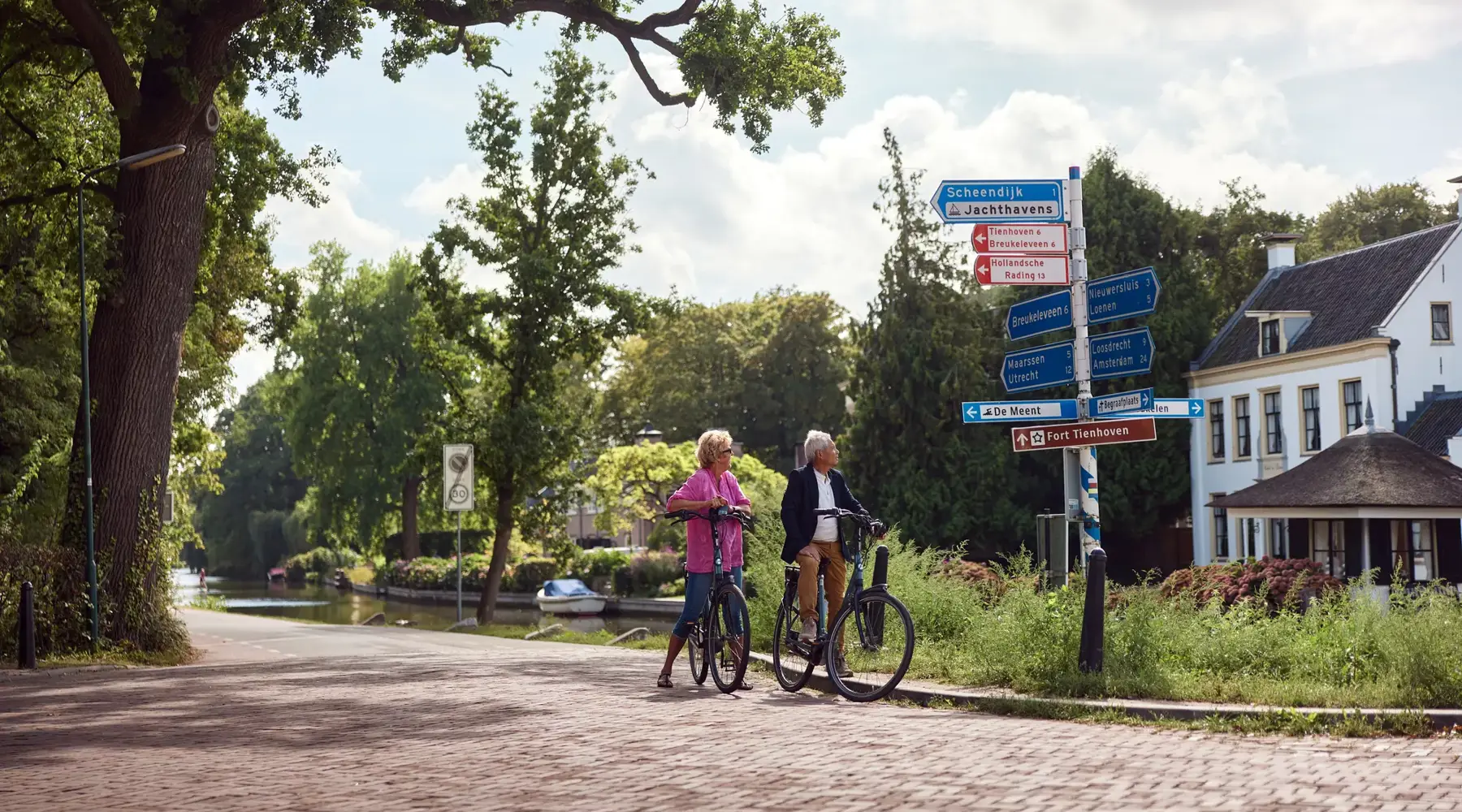 Man and woman on bicycles look at road signs