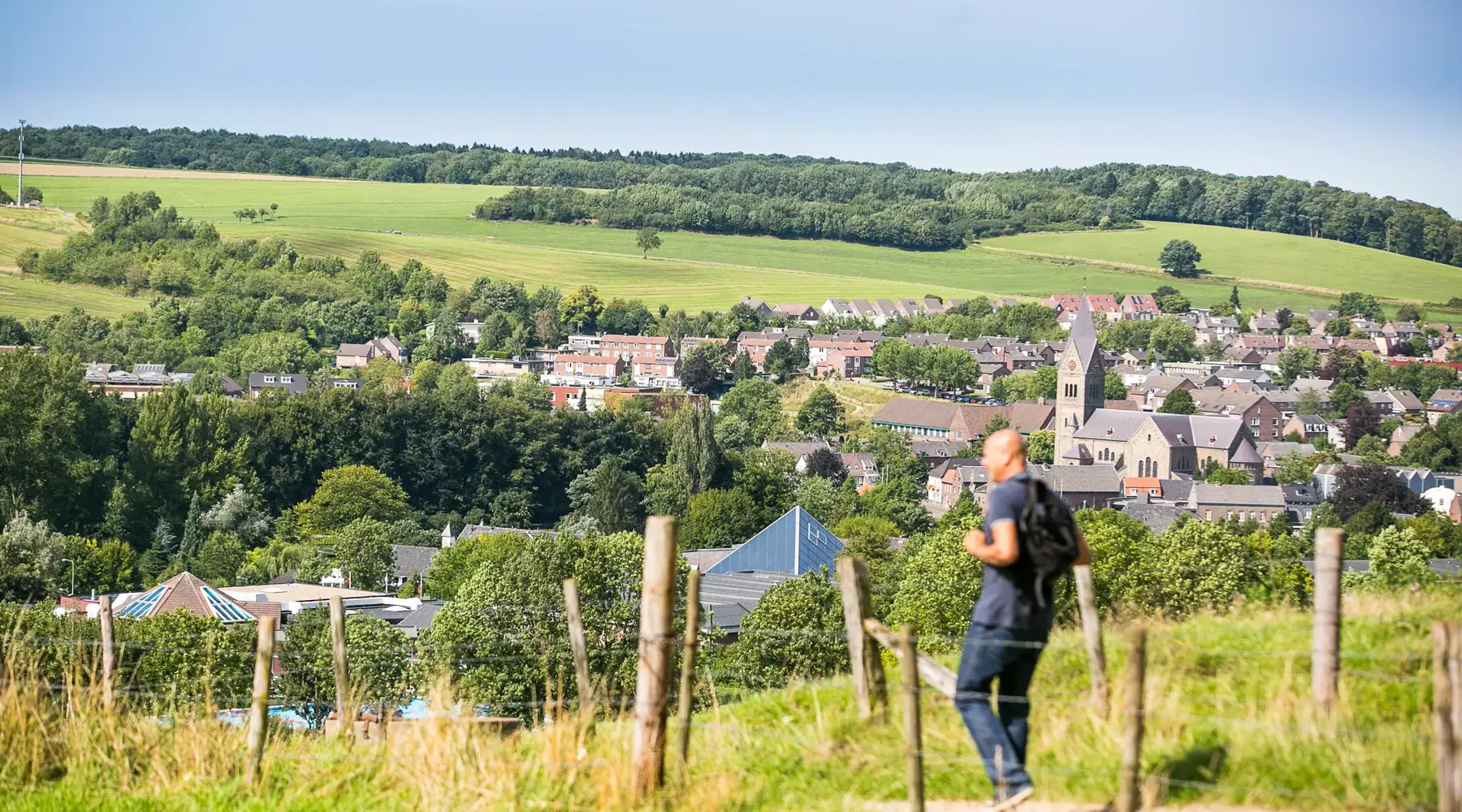 man wandelt in de heuvels van Limburg met op de achtergrond een dorp.