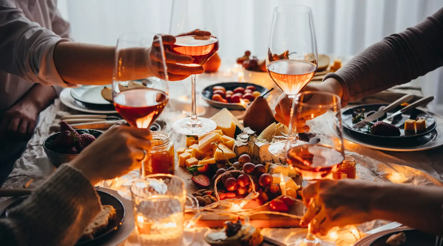 4 personen die proosten boven een kersterige tafel met hapjes