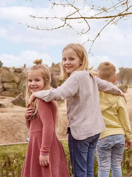Kinder stehen zusammen bei den Elefanten im Zoo