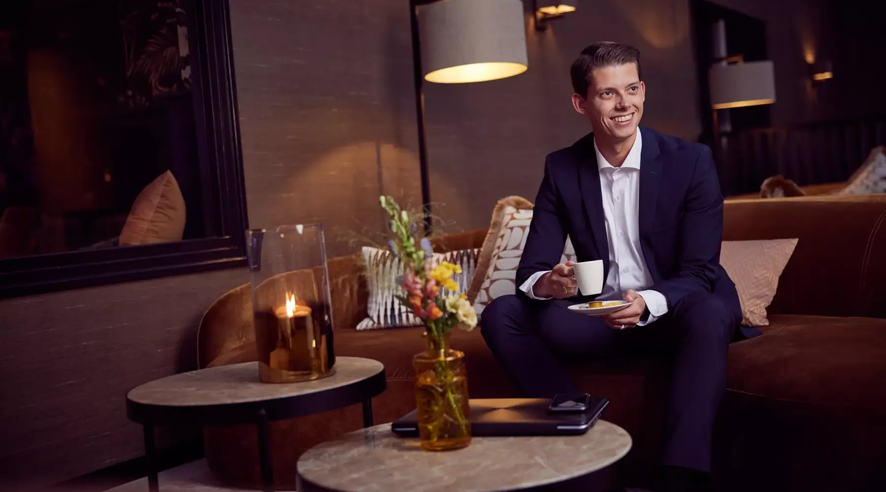 Man sitting in the lobby with a cup of coffee.