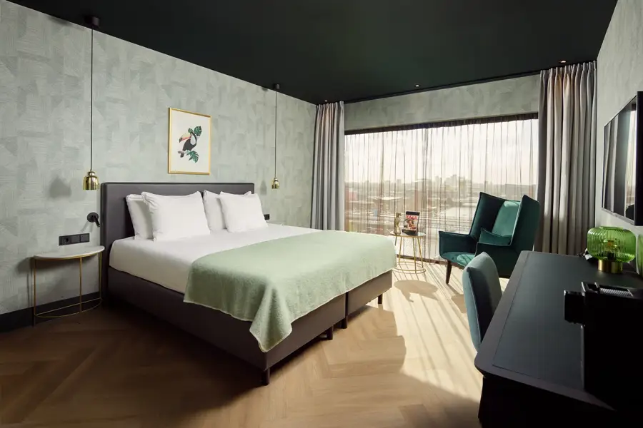 Comfort kamer met modern interieur, zithoek en uitzicht over Amsterdam
