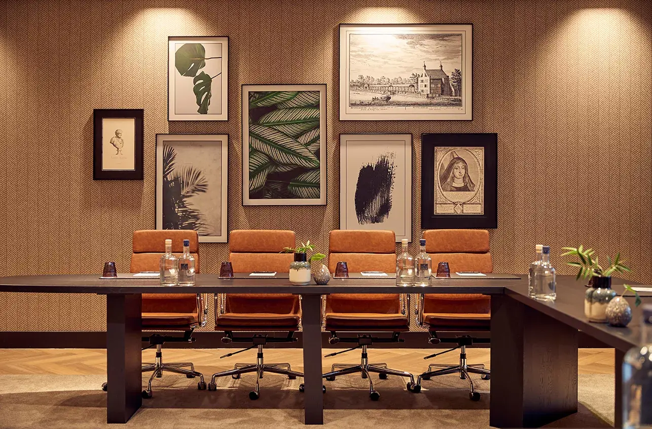 Salle de réunion avec des chaises marron et des tableaux sur le mur. 