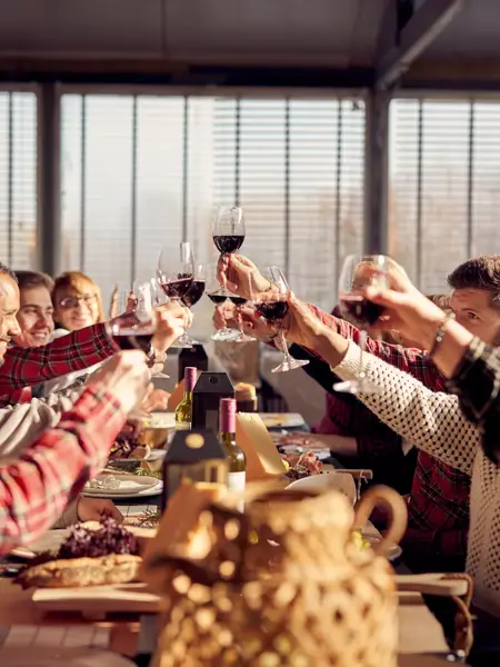 Groupe trinquant avec du vin rouge pendant un dîner de Noël festif.