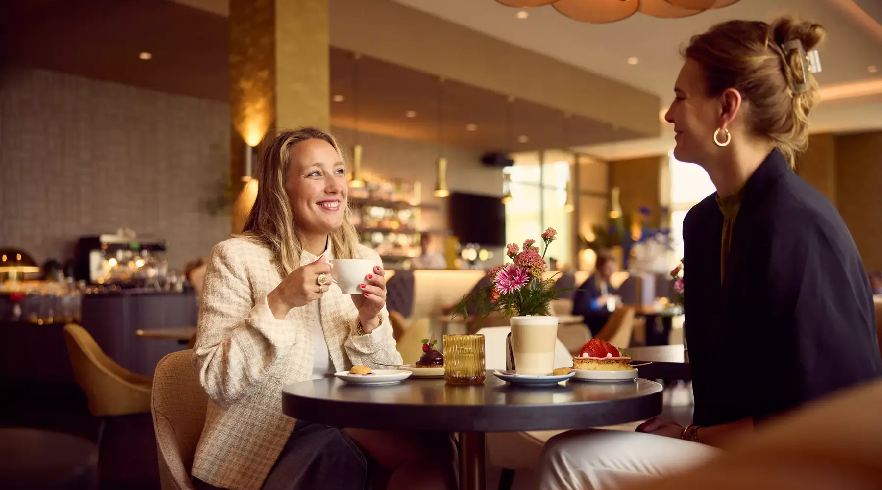 Zwei Frauen in der Hotelbar mit Kaffee und Gebäck.